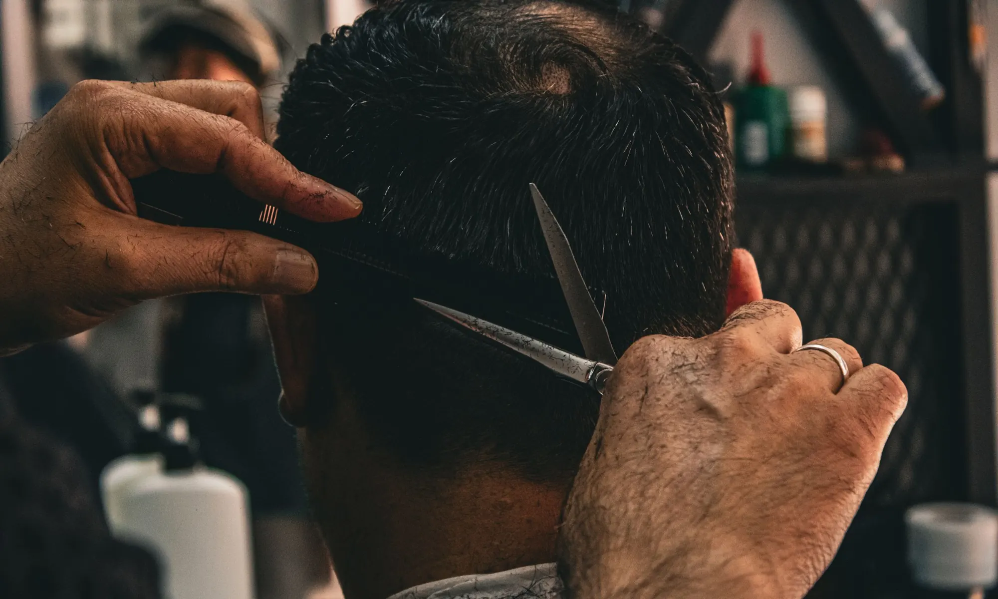 Mains de barbier coupant aux ciseaux la nuque d'un client